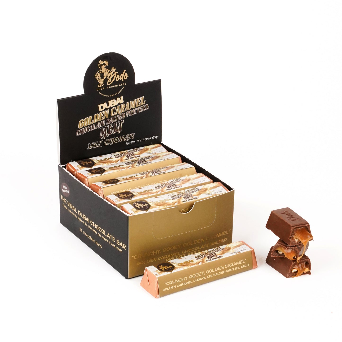 Display box of Dubai Golden Caramel chocolate bars with a single bar and a chocolate figurine on a white background.